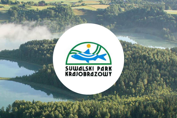 Zdjęcie przedstawia logo Suwalskiego Parku Krajobrazowego na tle jeziora